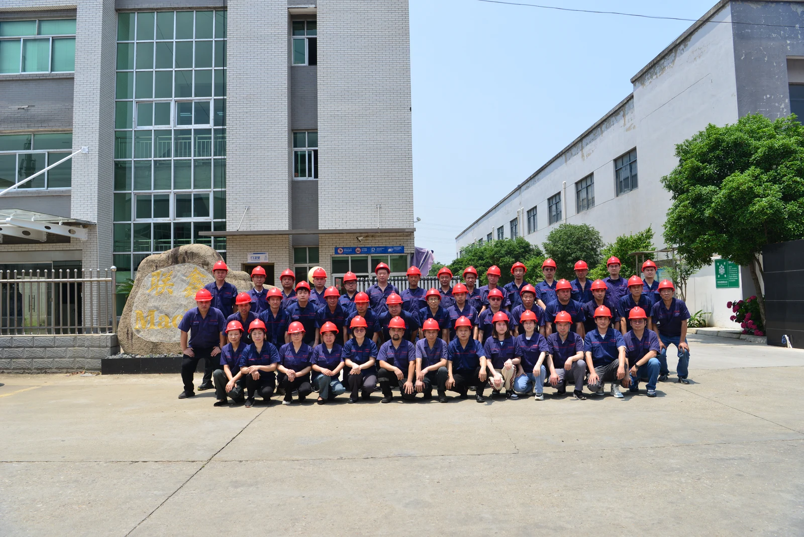 The LIANXIN production team gathered outside the factory in workwear and red safety helmets