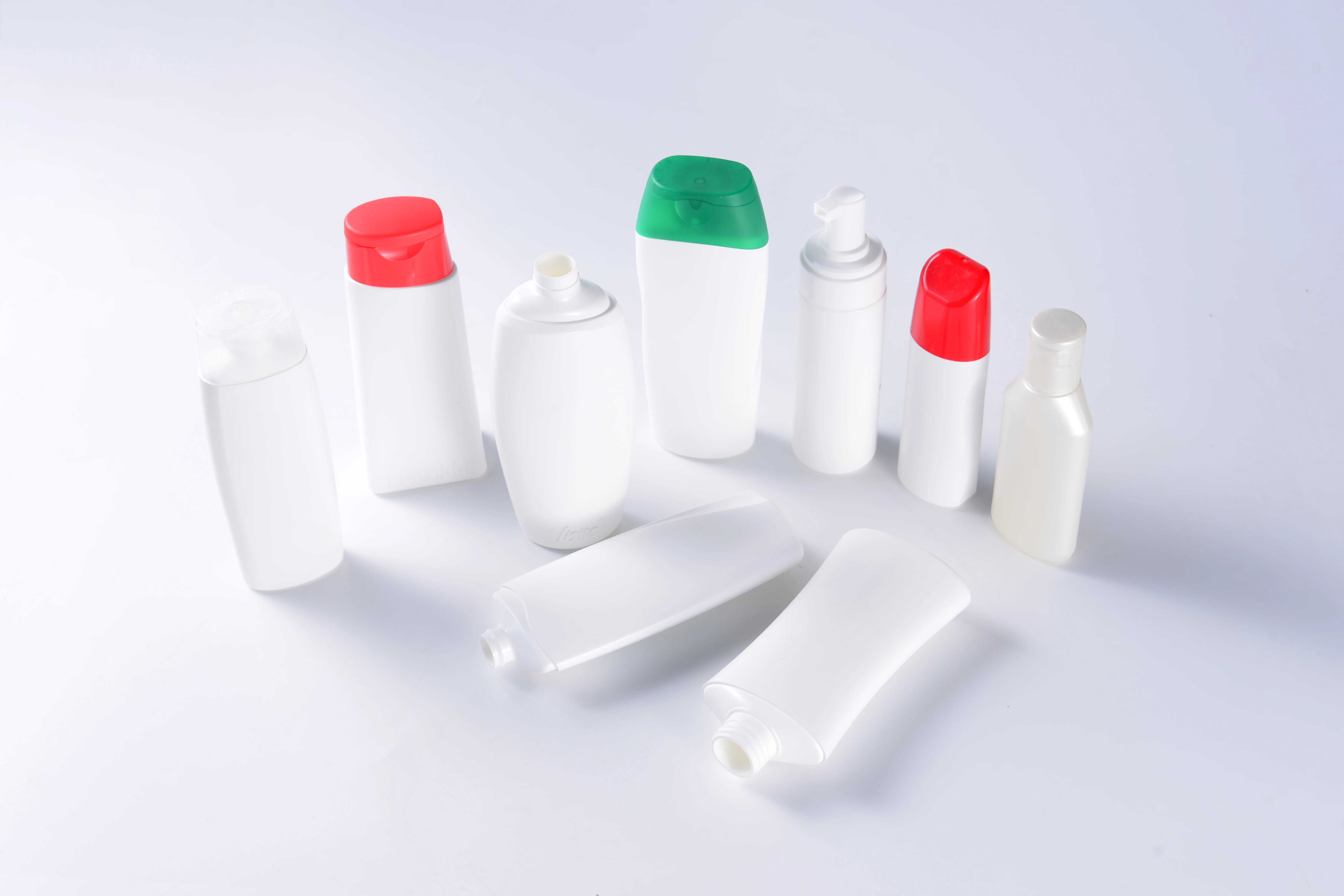 White shampoo and personal-care bottle samples with solid red and green closures on a clean background