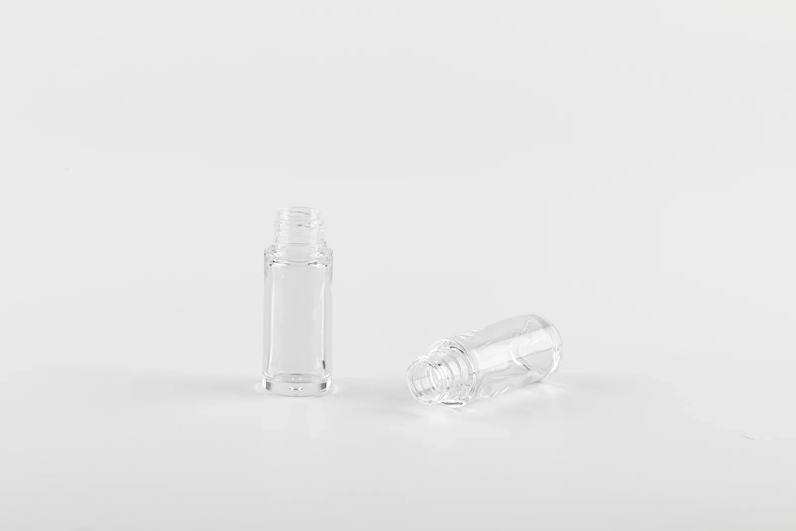 Two compact clear cylindrical cosmetic bottle samples