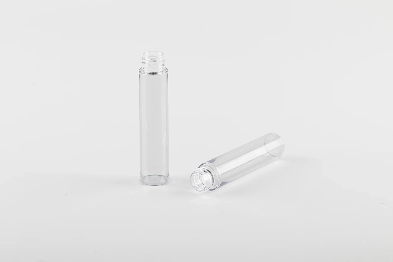 Two tall clear cylindrical cosmetic bottle samples