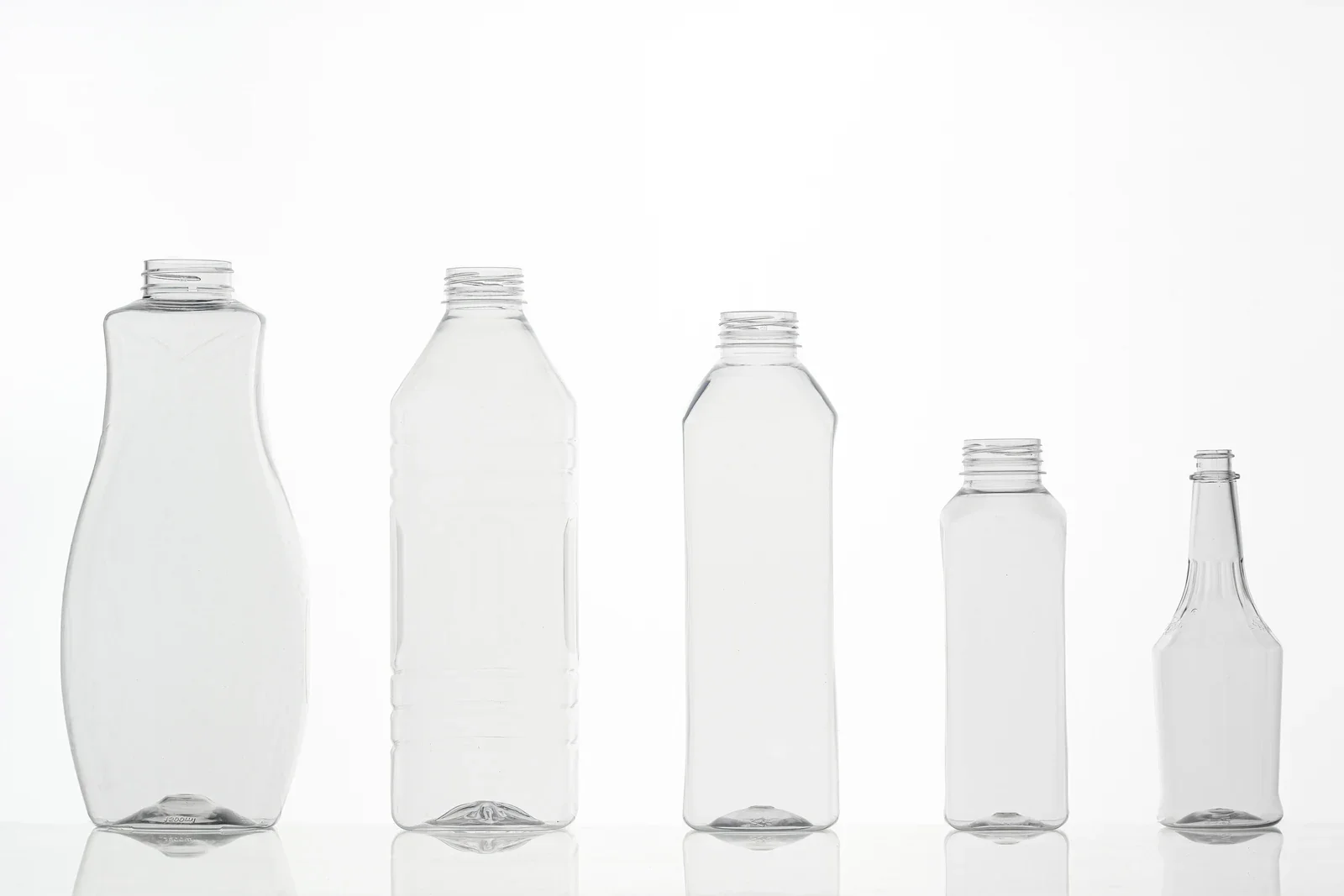 Five clear bottle samples with round, ribbed and shaped bodies