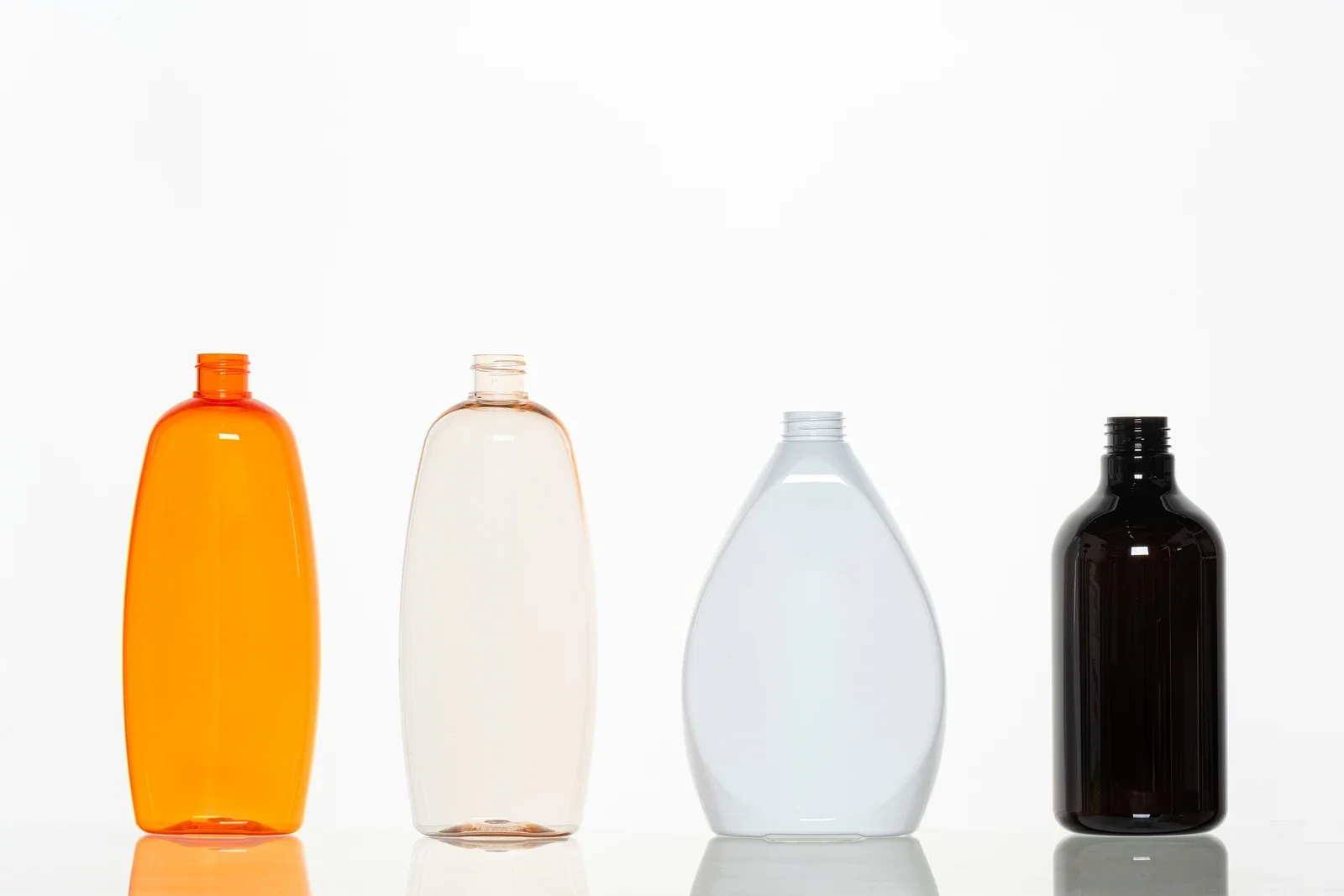 Four colored and clear bottle samples with oval and curved profiles
